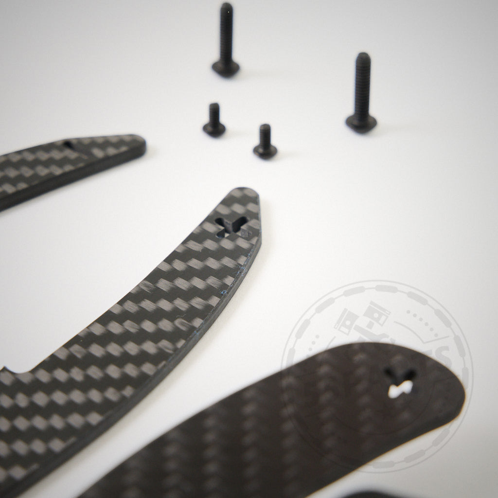 55Parts Special: Magnetische Schaltwippen V2 passend für BMW E9X M3, Carbonfaserteile und vier schwarze Schrauben sind auf einer weißen Oberfläche angeordnet.