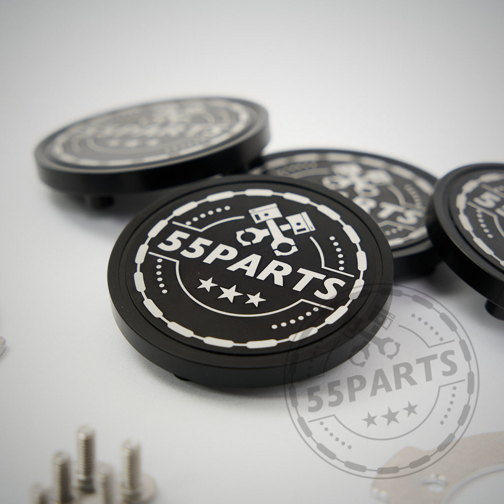 Das 55Parts Special: CNC gefräste, verschraubte Radnabendeckel für ProTrack One Felgen aus Aluminium sind rund und werden im Hintergrund von Schrauben und ähnlichen Teilen umgeben gezeigt.