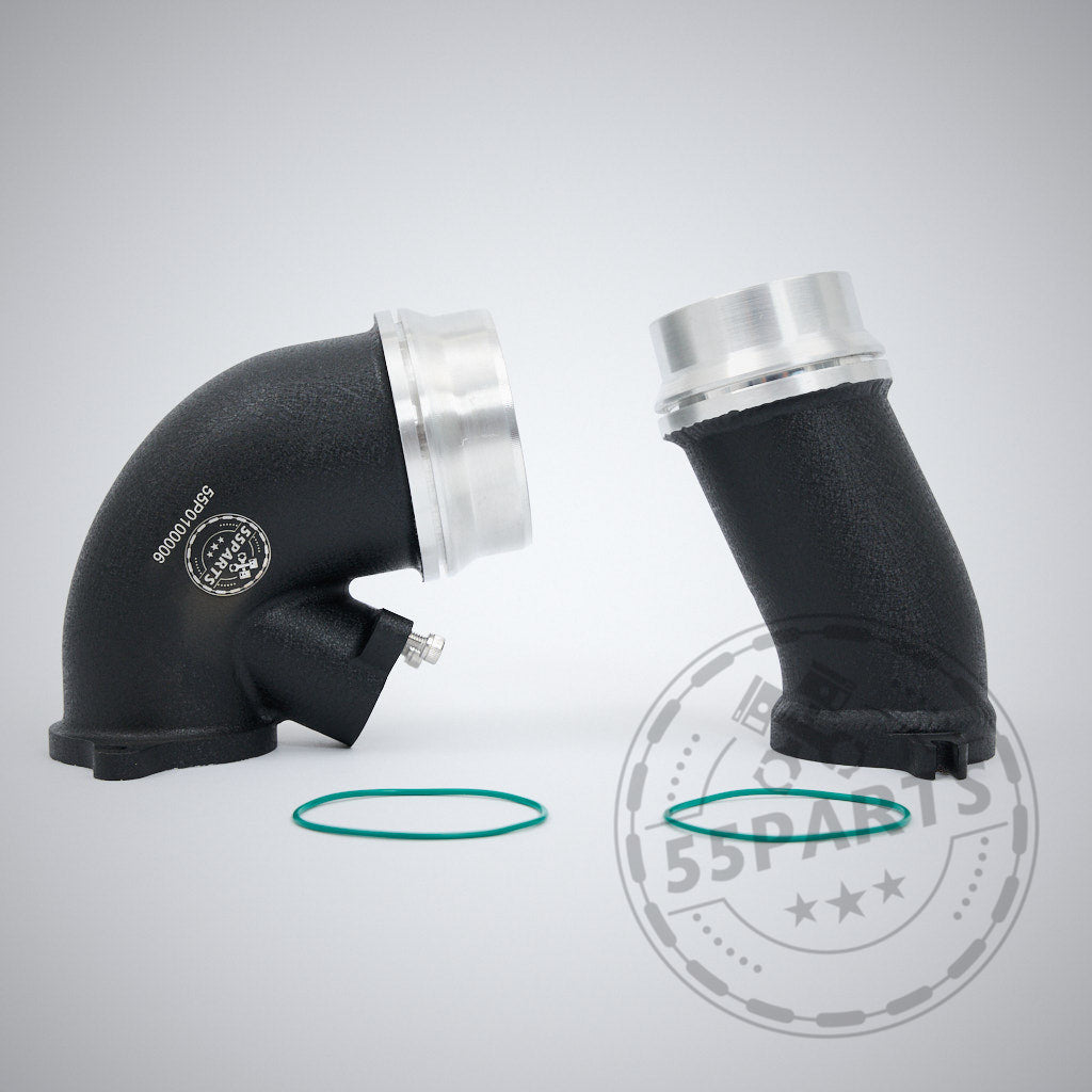 Zwei schwarze 55Parts High Flow Turbo Inlet Fittings mit silbernen Enden und grünen O-Ringen, entwickelt für BMW G87 M2, G80/G81 M3, und G82/G83 M4 S58 Motoren, dargestellt auf hellgrauem Hintergrund.