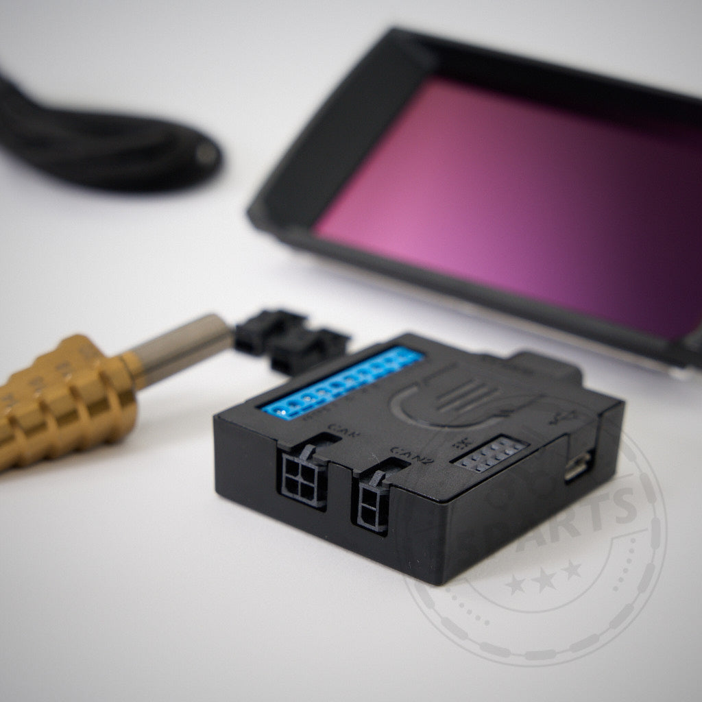 Nahaufnahme elektronischer Komponenten, darunter ein Stecker, ein Bohrer und das AK Motion DataDisplay NextGEN-Gerät passend für BMW-Modelle von AK Motion.