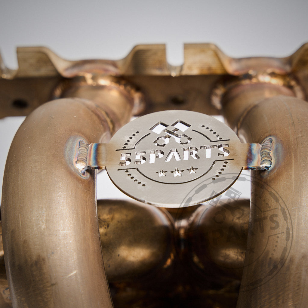 Nahaufnahme des 55Parts Special Big Turbo Kit 1000PS für B58 Gen.1 (F2X, F3X, G3X-Serie und mehr), mit einem Metallauspuffkrümmer mit „55Parts“-Logoplatte – perfekt für Turbo-Setups und Leistungssteigerungen.