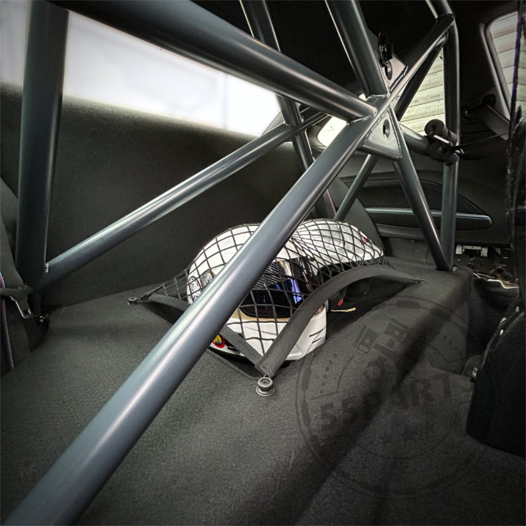 Ein 55Parts Clubsport Innenraum Ausbau mit Helmfach sichert einen Rennhelm hinter dem Clubsportbügel in einem mit Schalensitzen ausgestatteten BMW F-Serie 1er, 2er (inkl. M2) oder 4er (inkl. M4).