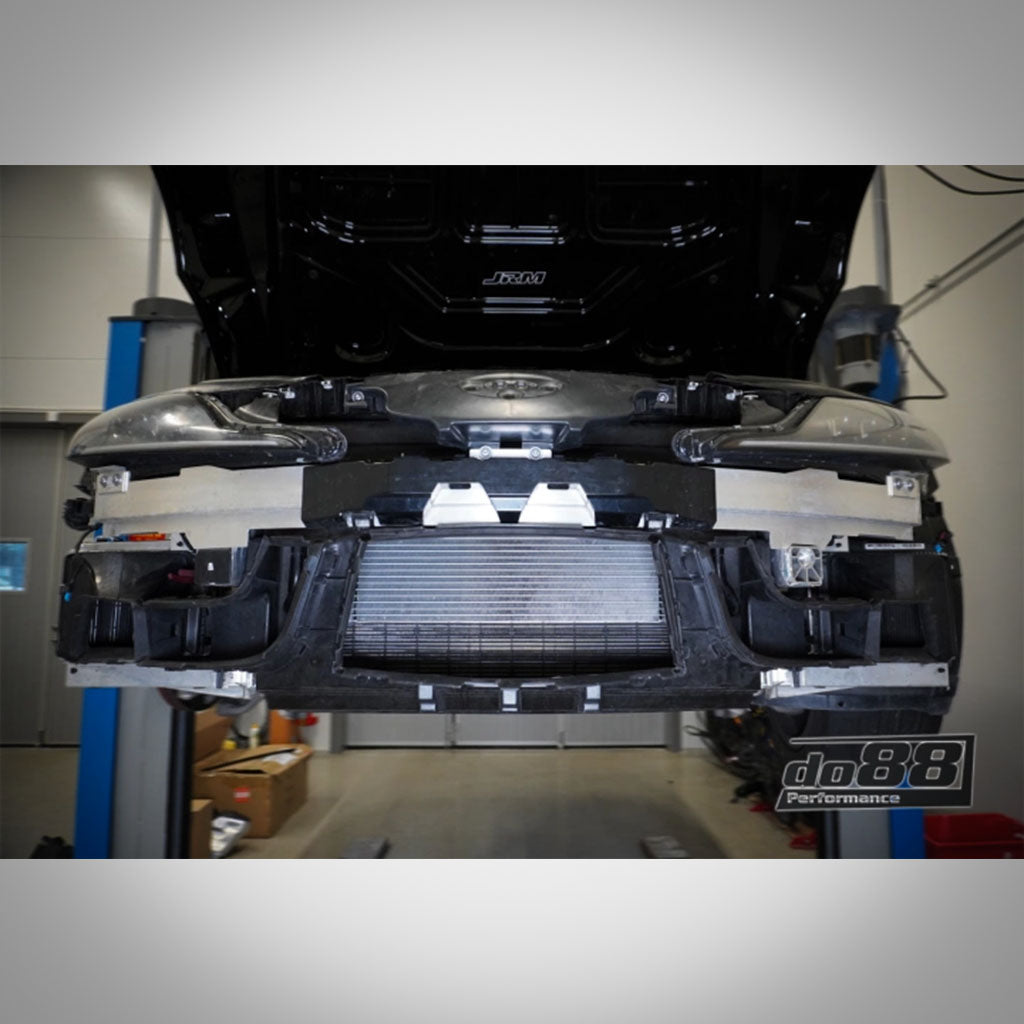Vorderansicht eines Autos in einer Garage mit entfernter Stoßstange. Zu sehen ist der do88 GETRIEBEÖLKÜHLER passend für BMW G42 M240i, G2X 330e/M340i/M440i, G29 Z4 M40i oder Toyota Supra A90/91 (B58 Gen 2), der die Kühlleistung verbessert.