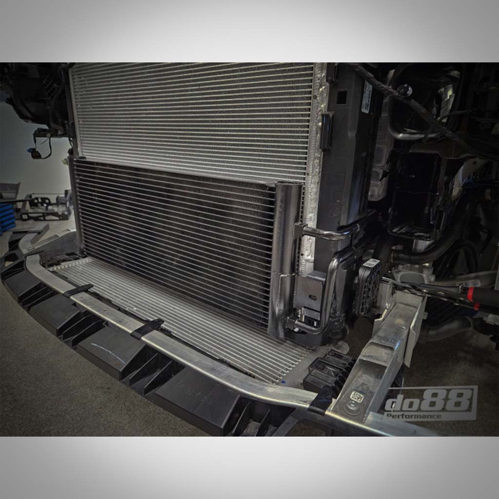 Nahaufnahme eines do88 DO88 GETRIEBEÖLKÜHLER passend für BMW G87 M2, G80/G81 M3 und G82/G83 M4 S58, eingebaut im Kühlsystem eines Fahrzeugs, mit sichtbarem do88 Performance-Branding.