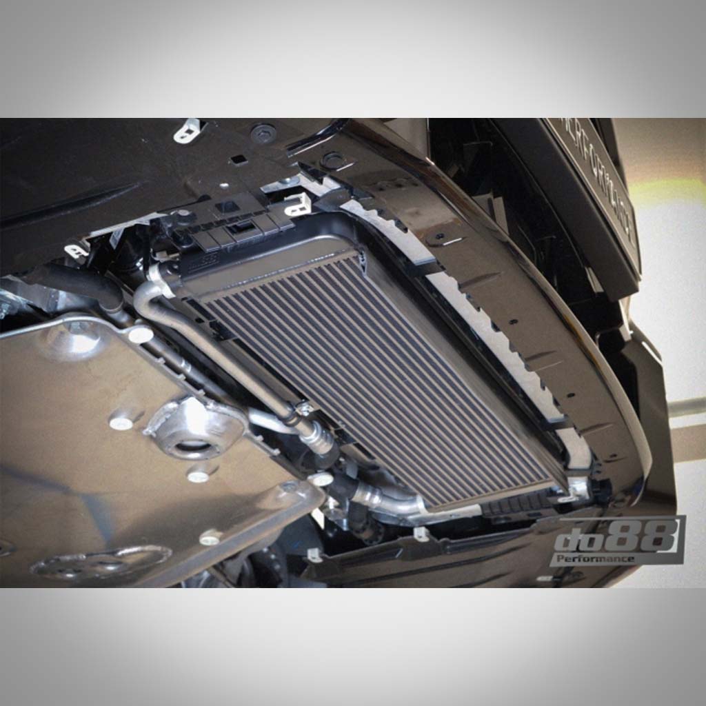Nahaufnahme des do88 Upgrade-Motorölkühlers, passend für BMW G87 M2, G80/G81 M3, G82/G83 M4 S58, unter dem Fahrzeug installiert, um Motorkühlung und Leistung zu verbessern.