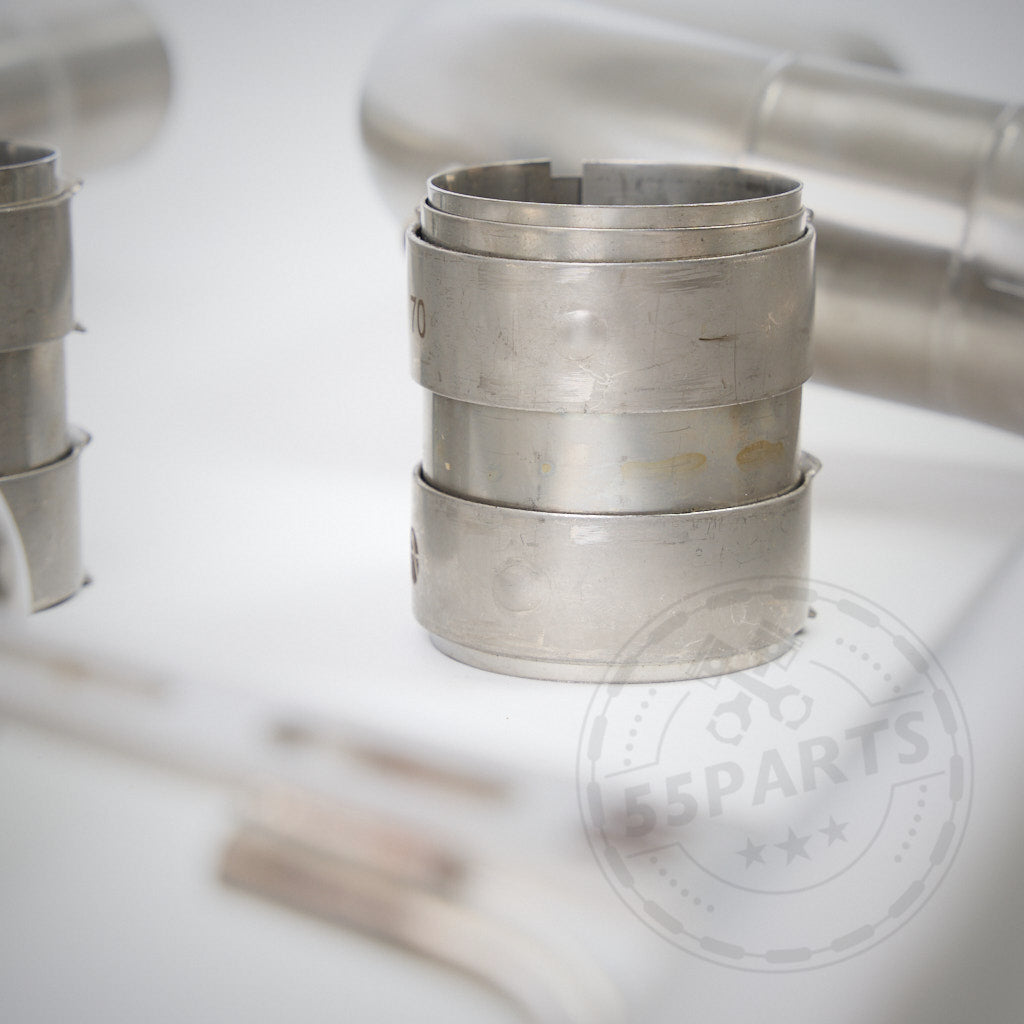 Nahaufnahme einer 55Parts Special 3" ECE-Abgasanlage passend für BMW G8x-Modelle (G81, G82, G83, G87 M2/M3/M4 Competition) mit S58-Motor, die ein metallisches Rohrfitting vor unscharfen Autoteilen im Hintergrund zeigt.