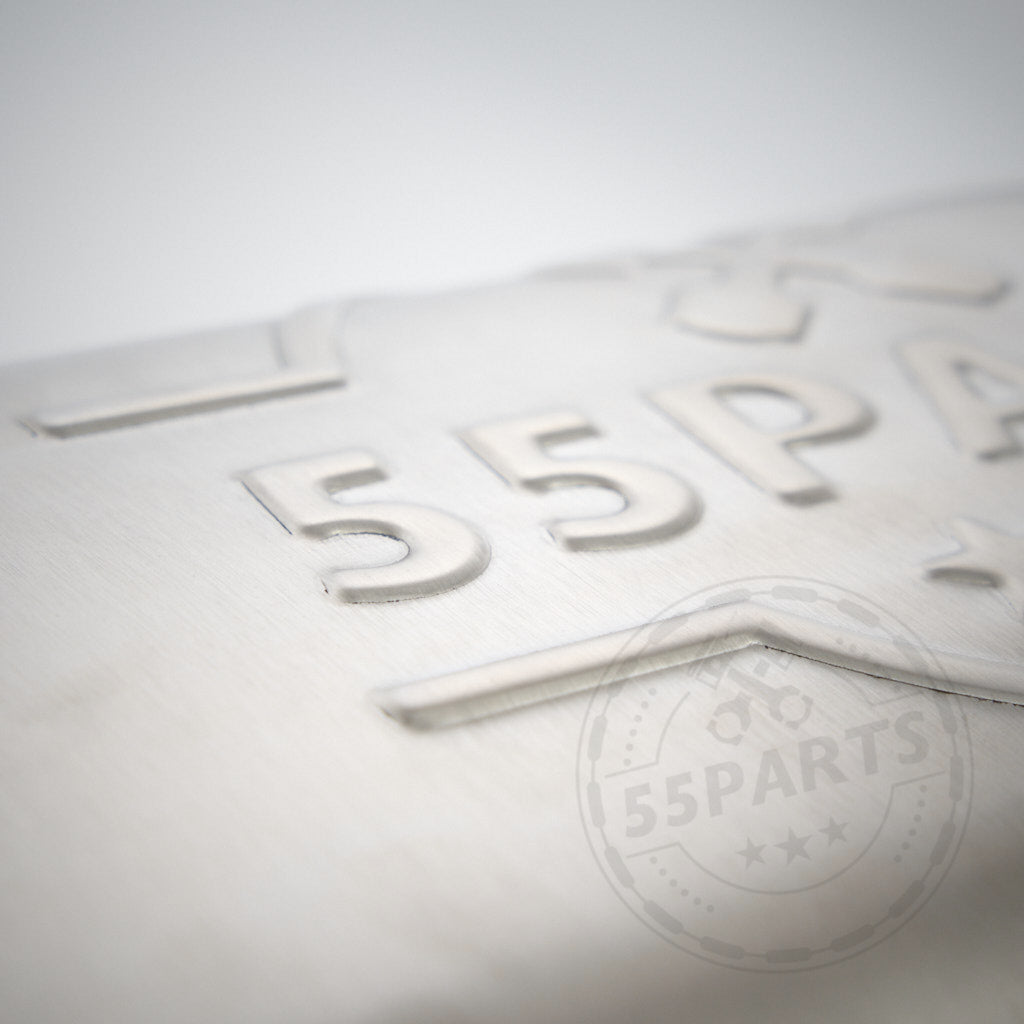 Nahaufnahme einer metallischen Oberfläche mit geprägtem 55Parts-Logo, Teil des 55Parts-Specials: 3" ECE-Abgasanlage passend für BMW G8x-Modelle wie G81, G82, G83 und G87 M2/M3/M4 (Competition) mit S58-Motor.