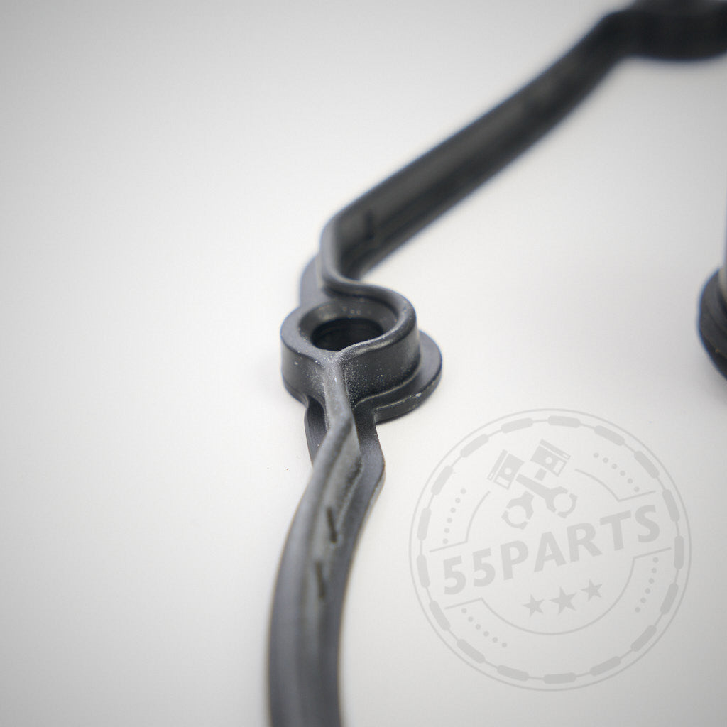 Nahaufnahme einer schwarzen Gummidichtung mit runder Öffnung auf weißem Hintergrund, entworfen für 55Parts. Exklusiv: Einbauset Ventildeckel passend für BMW E9x M3 (S65 Motor). Teilweises Logo sichtbar.