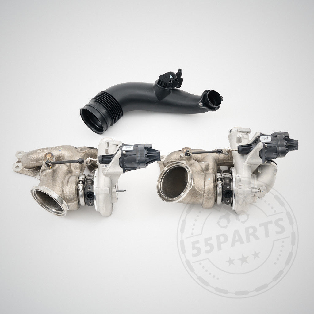 Auf hellem Untergrund mit 55Parts Logo-Wasserzeichen sind zwei Ladermanufaktur Upgrade Turbolader LM700-LM900 und ein schwarzes Ansaugrohr passend für BMW F80, F82, F87 M2C, M3, M4 (S55) abgebildet.
