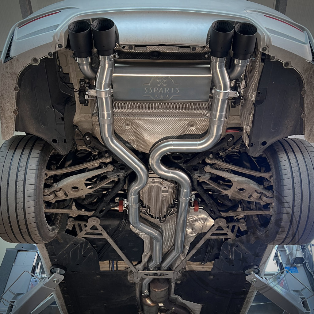 Unteransicht eines Autos auf einer Hebebühne mit der 55Parts Special 3" ECE Equal Length Abgasanlage mit glänzenden Metallrohren und Endschalldämpfern, passend für alle BMW F8x M2 Competition-, M3- und M4-Modelle.