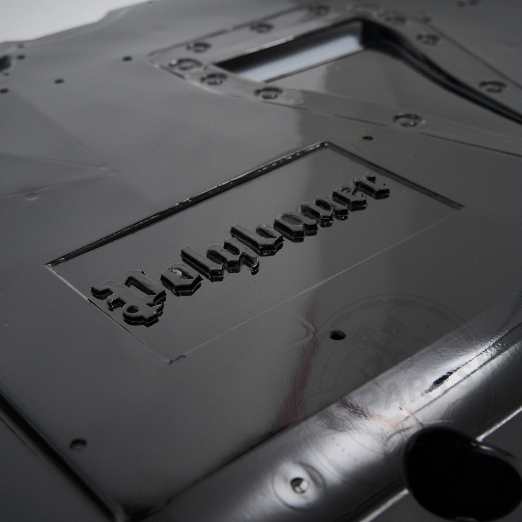 Nahaufnahme eines glänzend schwarzen GFK-Unterbodens inkl. Differential- und Getriebekühlung & Polybauer Automotive, entworfen für Toyota GR Yaris, geprägt mit Jellylayer im gotischen Schriftzug.