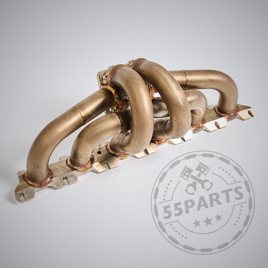 Das 55Parts Special: Big Turbo Kit 1000PS B58 Gen.1 verfügt über einen Metall-Auspuffkrümmer mit vier gebogenen Rohren, entwickelt für die Modelle F2X 1er/2er, F3X 3er/4er, G3X 5er/6er/G1X 7er, G01 X3 und G02 X4. Abgebildet auf hellgrauem Hintergrund.