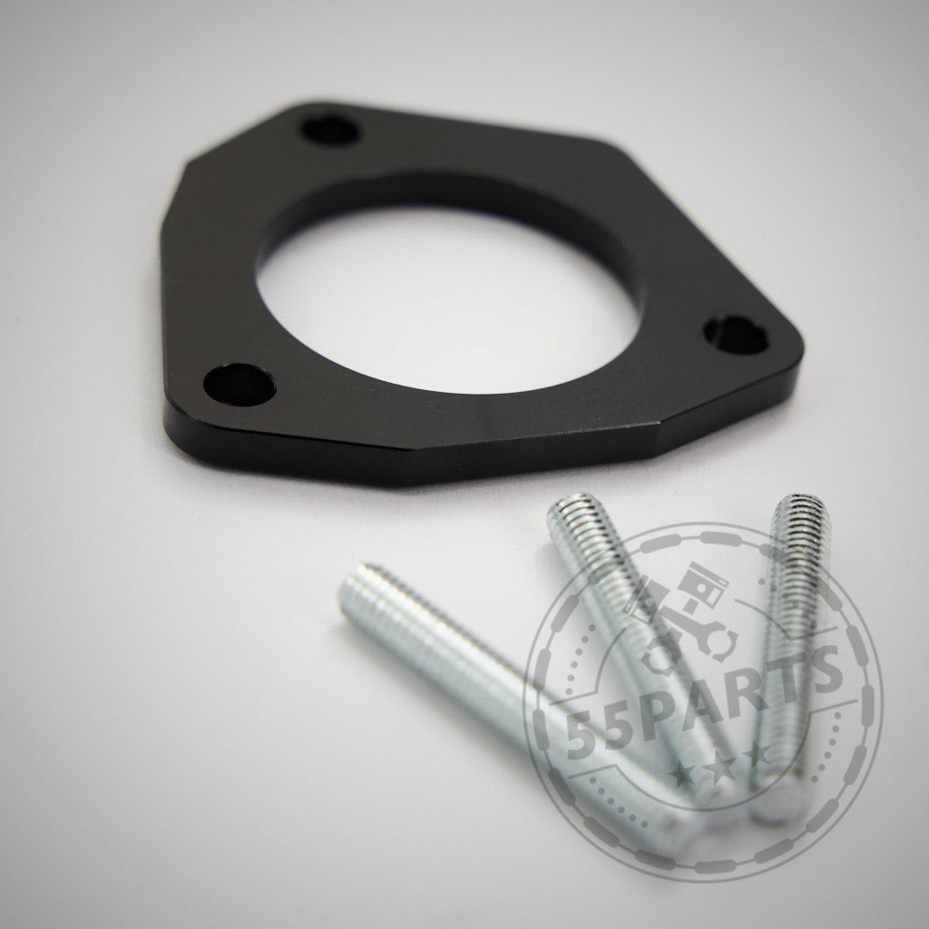 Eine schwarze Metalldichtung, der S55 Adapter für Ölmengenerhöhung F8x (M2c, M3, M4), mit drei Löchern neben silbernen Schrauben, abgebildet auf einer weißen Fläche.