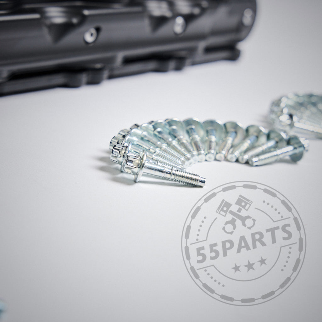 Eine geschwungene Reihe glänzender Aluminiumschrauben auf einer weißen Oberfläche mit einem verschwommenen Autoteil und dem 55Parts EXKLUSIV: Aluminium-Ventildeckel passend für BMW N55 Motor (M)135i, M235i, 335i, 435i, 535i, 640i-Logo im Vordergrund.