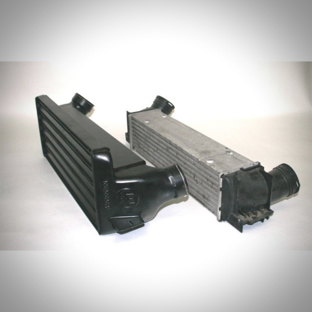 Ein schwarzer Aftermarket-Ladeluftkühler Wagner Tuning Evo 1 Performance und ein silberner Original-Ladeluftkühler passend für BMW 135i, 1er M Coupé und 335i(x) N54/N55 E-Serie werden nebeneinander auf weißem Hintergrund angezeigt.