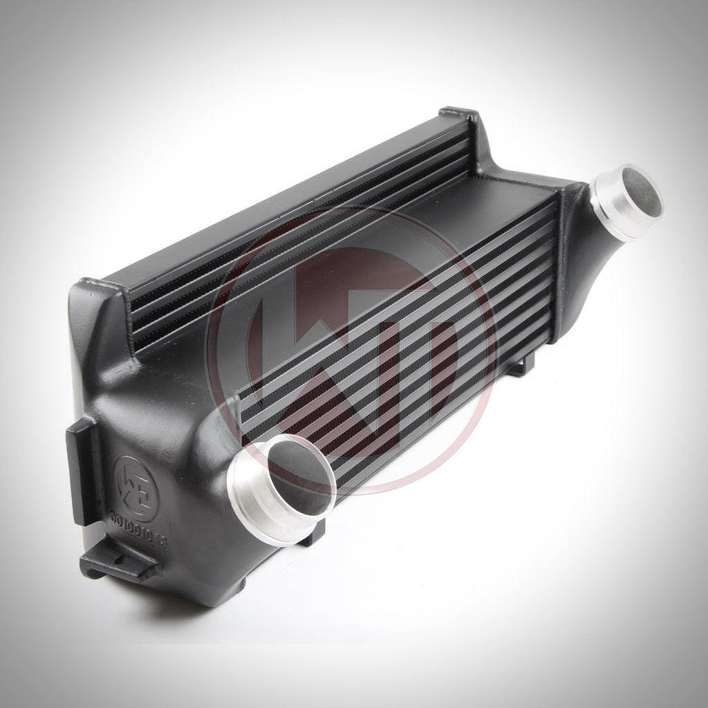 Der Wagner Tuning Evo 1 Competition Ladeluftkühler passend für BMW F2x, F3x ist ein schwarzer Aluminium-Ladeluftkühler mit zwei silbernen Einlass- und Auslassrohren, abgebildet auf weißem Hintergrund.