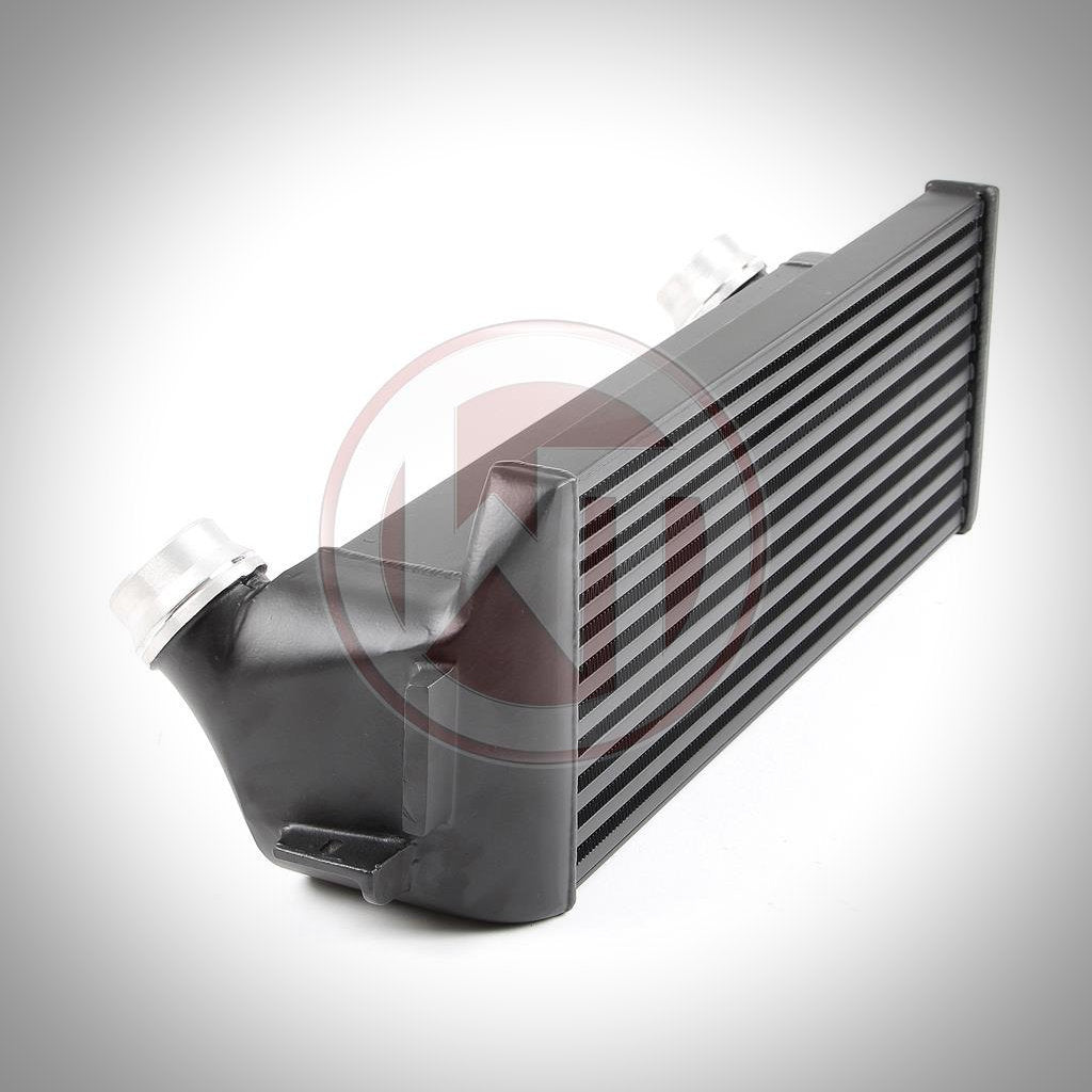 Ein Wagner Tuning Evo 1 Competition Ladeluftkühler in Schwarz mit silbernen Einlass- und Auslassrohren, konzipiert passend für BMW F2x/F3x, ideal für ein FBO-Setup, abgebildet auf weißem Hintergrund.