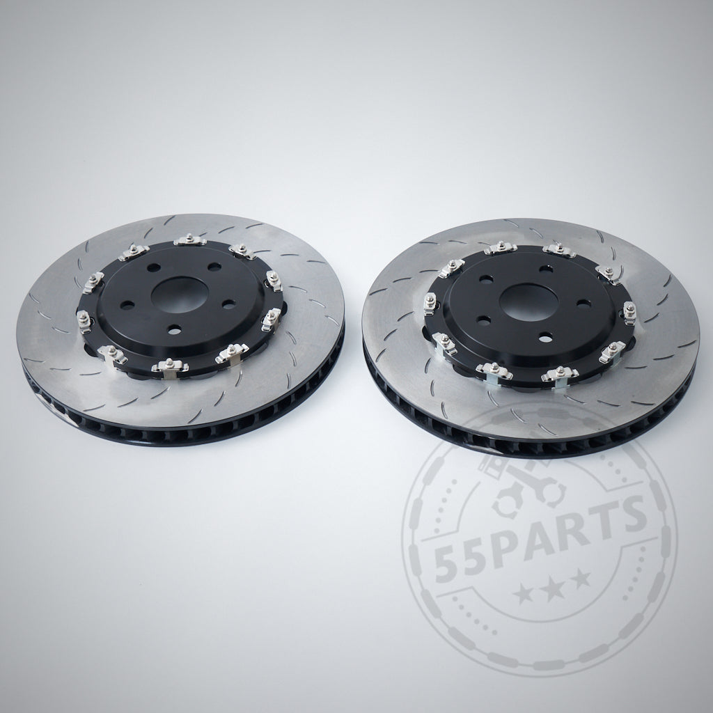 Two 55Parts Carbopad zweigeteilte, schwimmend gelagerte Bremsscheiben (380mm) passend für BMW M2, M3, M4 F8x mit schwarzen Zentren liegen nebeneinander auf hellgrauem Hintergrund.