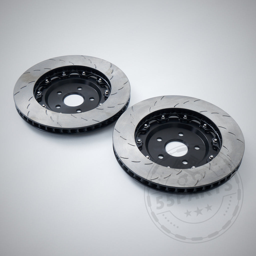 Two 55Parts Carbopad zweitteilige, schwimmend gelagerte Bremsscheiben (380mm) passend für BMW M2, M3, M4 F8x mit schwarzem Topf sind auf hellgrauem Grund zu sehen – ideal für Rennstrecken-Performance-Upgrades.