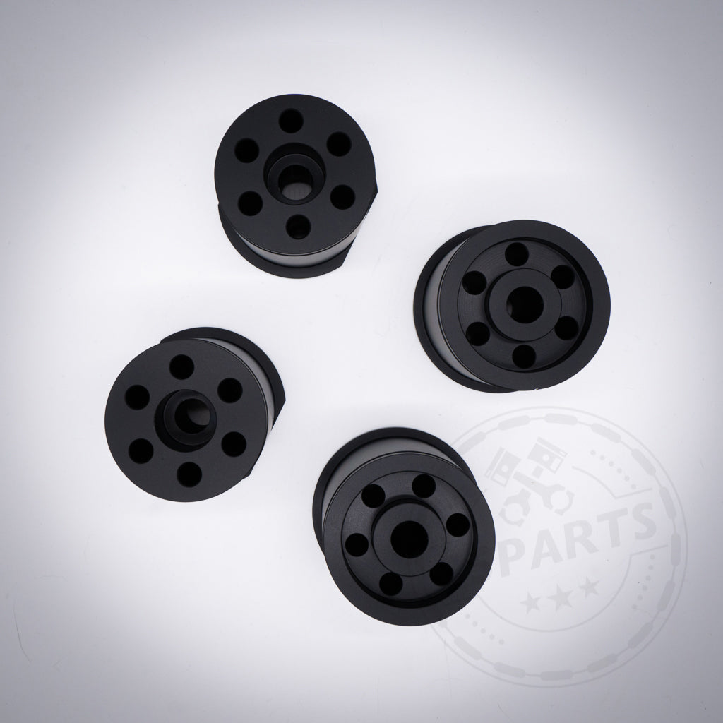 Set aus vier schwarzen Aluminium-Tonnenlagern Hinterachslagern, mit mehreren Löchern, angeordnet auf weißem Hintergrund; passend für BMW 1er (E8x, F2x), 2er (F2x), 3er (E9x, F3x), 4er (F3x), Z4 (G29) und Supra (A90).