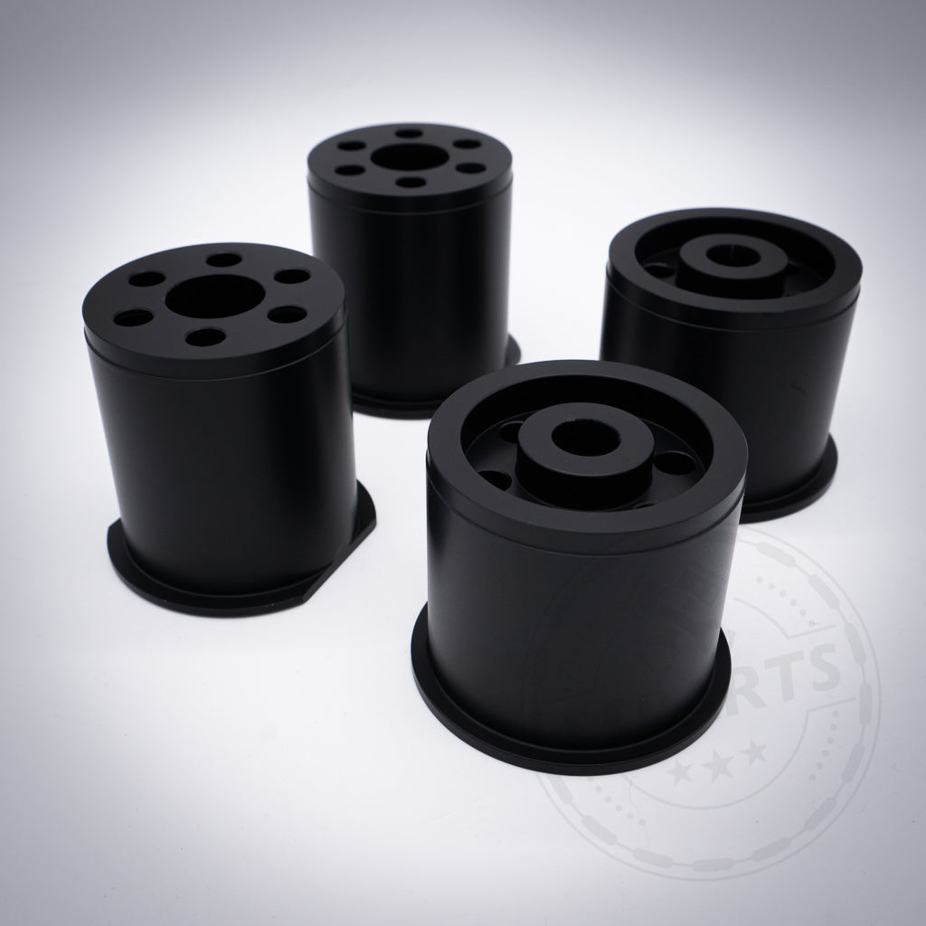 Vier schwarze zylindrische Aluminium-Tonnenlager, konzipiert als Hinterachslager passend für BMW 1er (E8x, F2x), 2er (F2x), 3er (E9x, F3x), 4er (F3x), Z4 (G29) und Supra (A90); ideal für Achsupgrades und Fahrzeugmodifikationen.