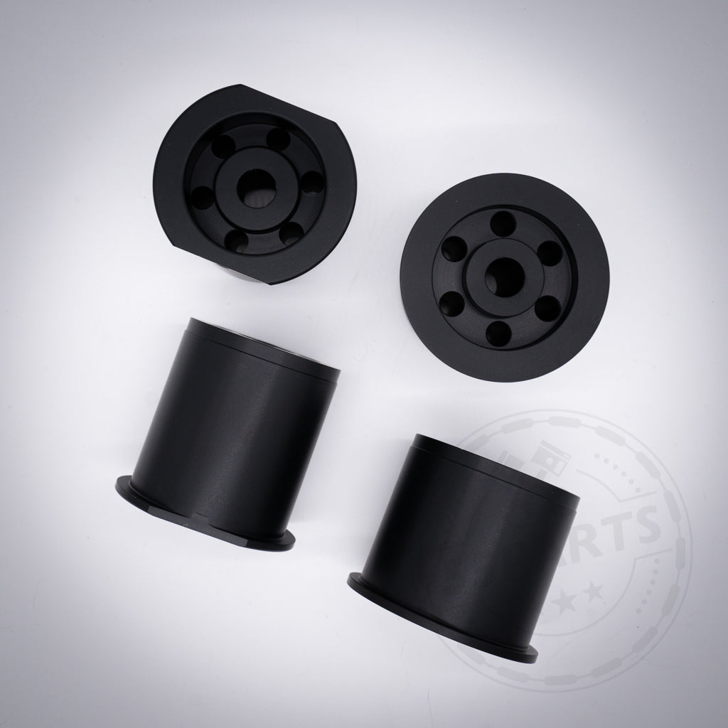 Vier schwarze Aluminium-Tonnenlager, konzipiert für die Fahrwerksoptimierung von BMW 1er, 2er, 3er, 4er, Z4 (G29) und Supra (A90), sind auf einer hellen Fläche angeordnet.