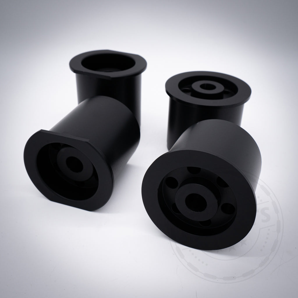 Vier schwarze zylindrische Aluminium-Tonnenlager-Hinterachsaufnahmen mit Flanschen, abgebildet auf weißem Untergrund; passend für BMW 1er (E8x, F2x), 2er (F2x), 3er (E9x, F3x), 4er (F3x), Z4 (G29) und Supra (A90) zur optimalen Fahrwerksoptimierung.