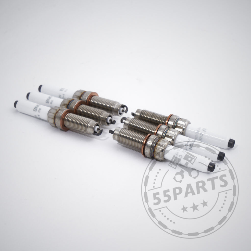 Sechs BMW Zündkerzen-Sets für 6-Zylinder-Modelle (M240i, M340i, M440i, G8x M2/M3/M4, X3M, A90 Supra B58) sind in zwei Reihen auf einer weißen Fläche mit einem 55Parts-Wasserzeichen in der Ecke angeordnet.