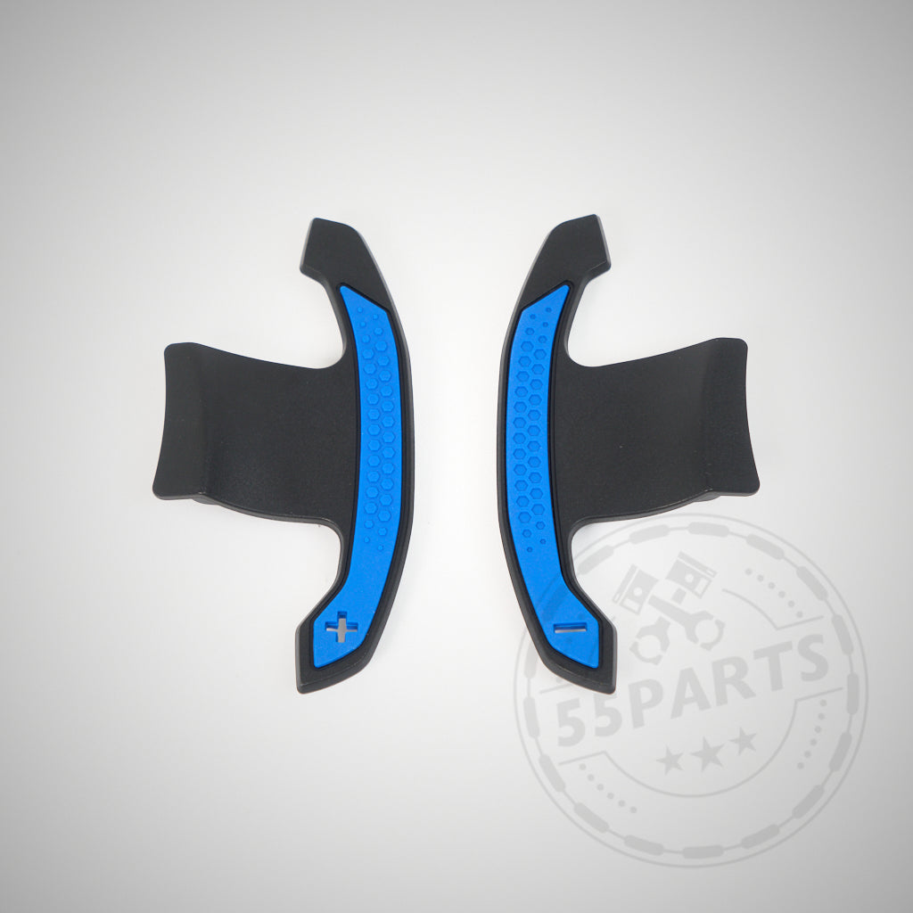 Zwei schwarz-blaue Carbon-Schaltwippen mit Plus- und Minus-Symbolen, entworfen passend für BMW 1/235 und 40i, 3/435 und 40i, M2, M3 und M4 F- und G-Serie, abgebildet auf hellem Hintergrund.