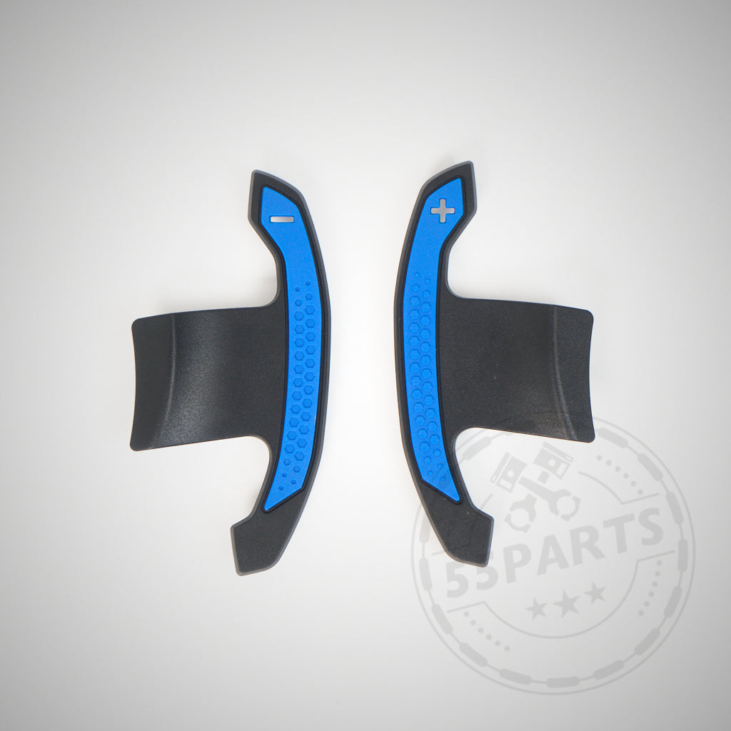 Auf hellgrauem Untergrund sind zwei blau-schwarze 55Parts Carbon Schaltwippen passend für BMW 1/2/3/4 35 und 40i, M2, M3 und M4 F- und G-Serie mit der Beschriftung Minus und Plus abgebildet.
