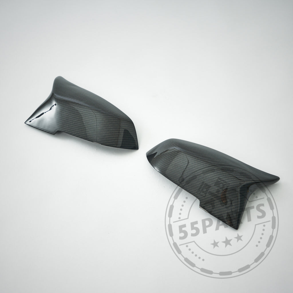 Zwei 55Parts Spiegelkappen Design Spiegelkappen passend für BMW F87 F2x F3x M2 M135i M140i M340i werden auf einem hellgrauen Hintergrund mit einem verblassten 55Parts Logo angezeigt.