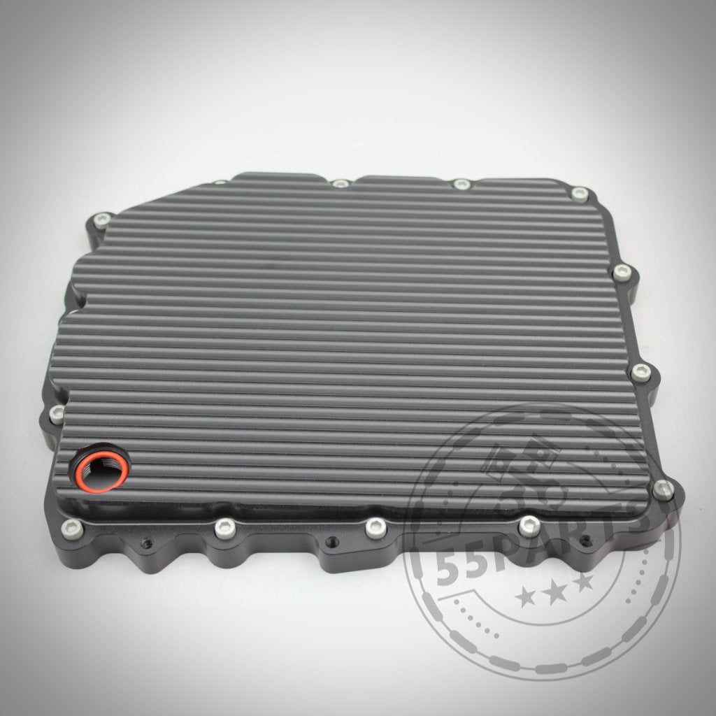 Rechteckige, gerippte schwarze 55Parts Exclusive DKG GS7D36BG Aluminium-Ölwanne passend für BMW 1/335i, M2(c), M3, M4, M5, M6 E- und F-Serie mit Randschrauben und einer rot umrandeten kreisrunden Öffnung.