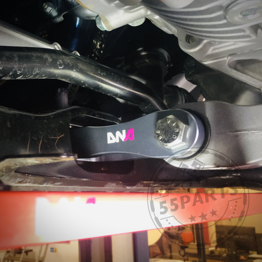 Nahaufnahme eines DNA Racing Upgrade Drehmoment Stütze-Motorlagers, das unter einem Toyota Yaris GR installiert ist, mit Wasserzeichen des Tuning Shop-Logos.