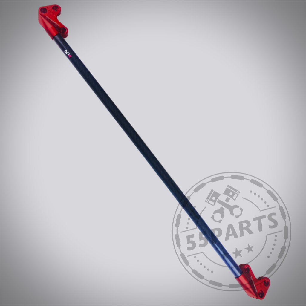 Die DNA Racing Carbon Domstrebe vorne für den Toyota Yaris GR verfügt über eine schwarze Carbonfaserstrebe mit roten Metallhalterungen, ideal für Fahrwerks-Upgrades, und ist auf einem hellgrauen Hintergrund abgebildet.