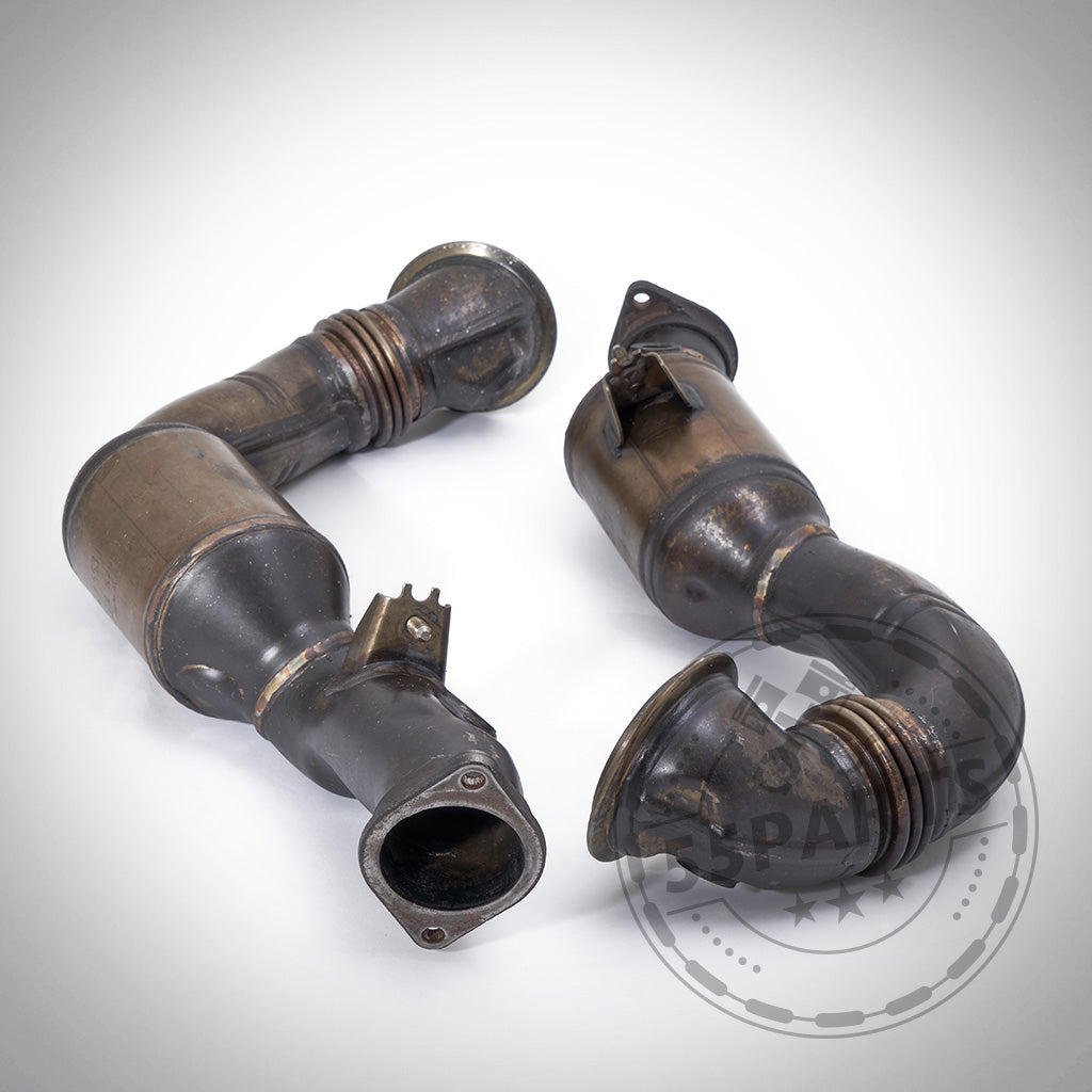 Zwei gebrauchte, umgebaute OEM-Downpipes passend für BMW 135i, 1er M Coupé, 335i N54, mit Flanschen und strömungsoptimiertem Downpipe-Design, abgebildet auf weißem Untergrund mit schwachem Logo-Wasserzeichen.