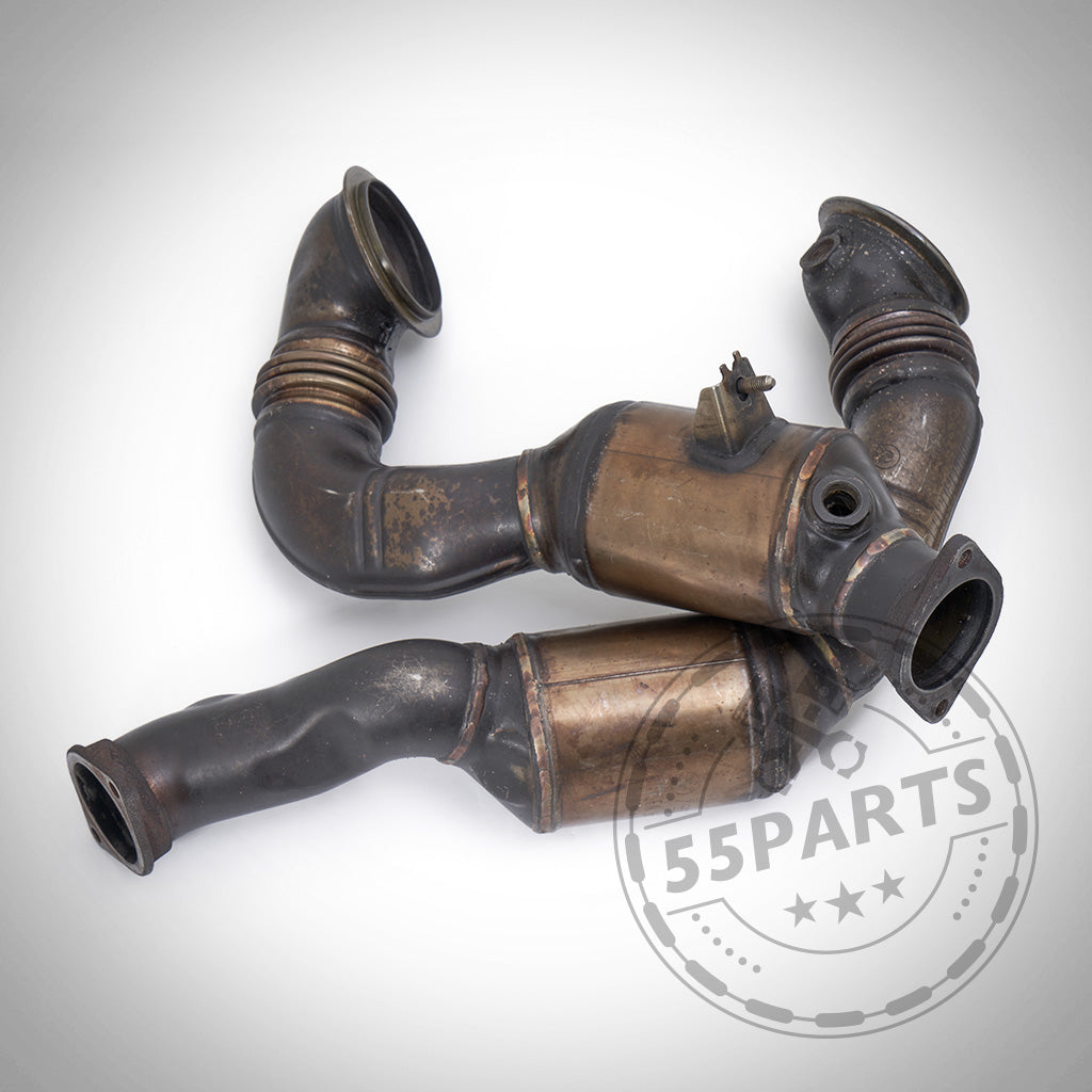 Drei gebrauchte umgebaute OEM Downpipes, kompatibel mit BMW 135i, 1er M Coupé und 335i N54, isoliert auf weißem Hintergrund.