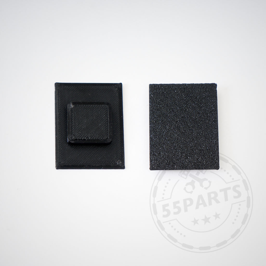 Zwei kleine schwarze rechteckige 3D-Druckeinsätze für Stoßstange mit kurzem Kennzeichen passend für Toyota Yaris GR liegen auf weißem Hintergrund, einer mit quadratischer Erhebung in der Mitte.