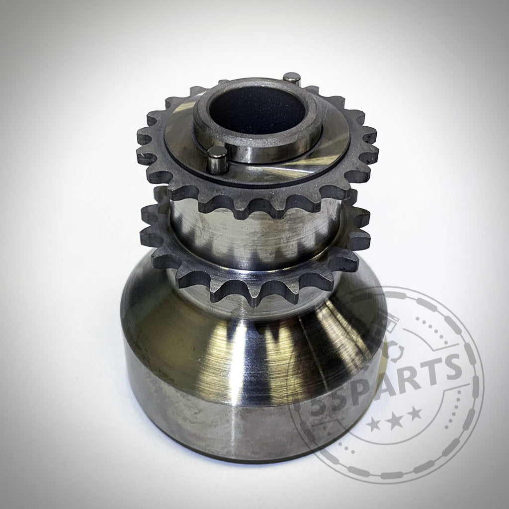 Glänzender Metallgetriebemechanismus mit zwei Kettenrädern auf Weiß, wie die 55Parts Exclusive Einteiliger Crank Hub Kurbelwellensicherung von Insane Performance passend für BMW M2 Competition, M3, M4 S55/N55/135i/335i/N54 – entwickelt für Spitzenleistung und Zuverlässigkeit.