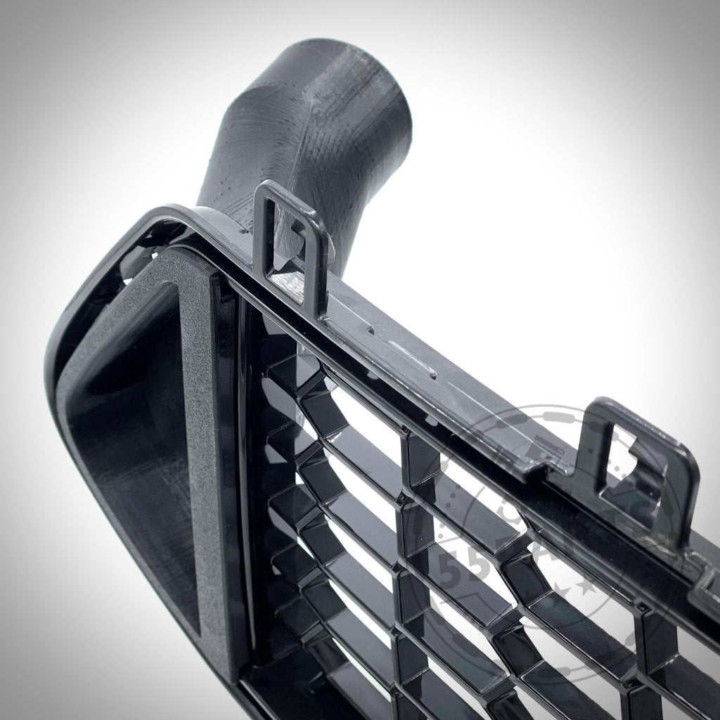 Nahaufnahme des 55Parts Exclusive Bremsbelüftungssets Bremskühlung passend für BMW M2 Competition und M2 CS S55, mit einem schwarzen Kunststoffgitter mit Entlüftung und Befestigungslaschen, fotografiert auf weißem Hintergrund.