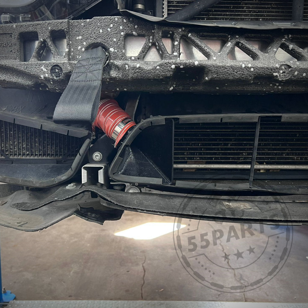 Nahaufnahme einer BMW M3/M4 F8x Frontstoßstange mit rotem Schlauch. Das exklusive 55Parts Bremsbelüftungsset für verbesserte Bremskühlung und Leistungssteigerungen ist hervorgehoben. Großes „55Parts“-Wasserzeichen.