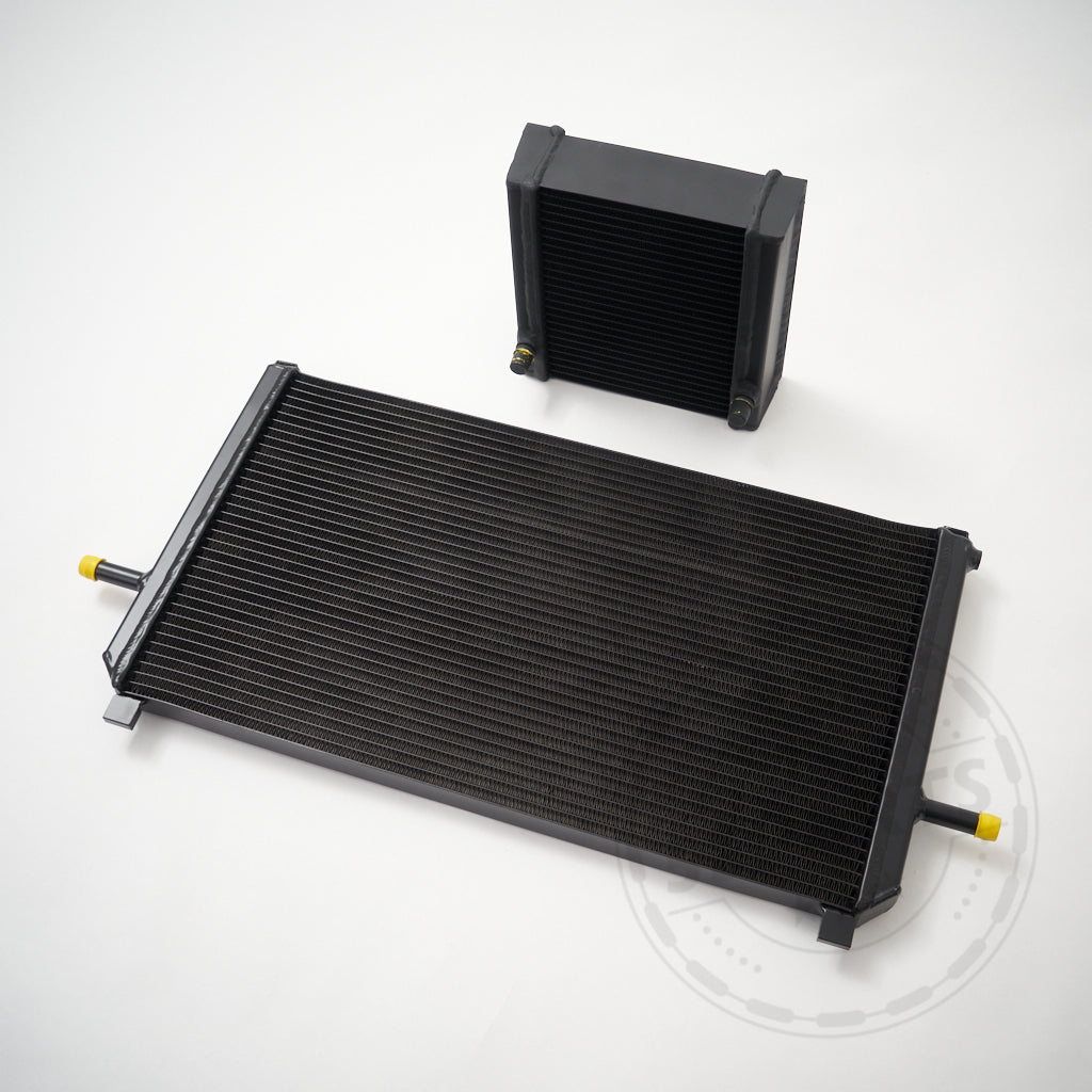 Zwei schwarze 55Parts Ladeluftkühler Upgrade (Wasser) – ein großer und ein kleiner – für Mercedes Benz M133 AMG A45, CLA45 und GLA45 (W176/C117/X156) sind auf weißem Hintergrund abgebildet. Perfekte FBO-Konfiguration.