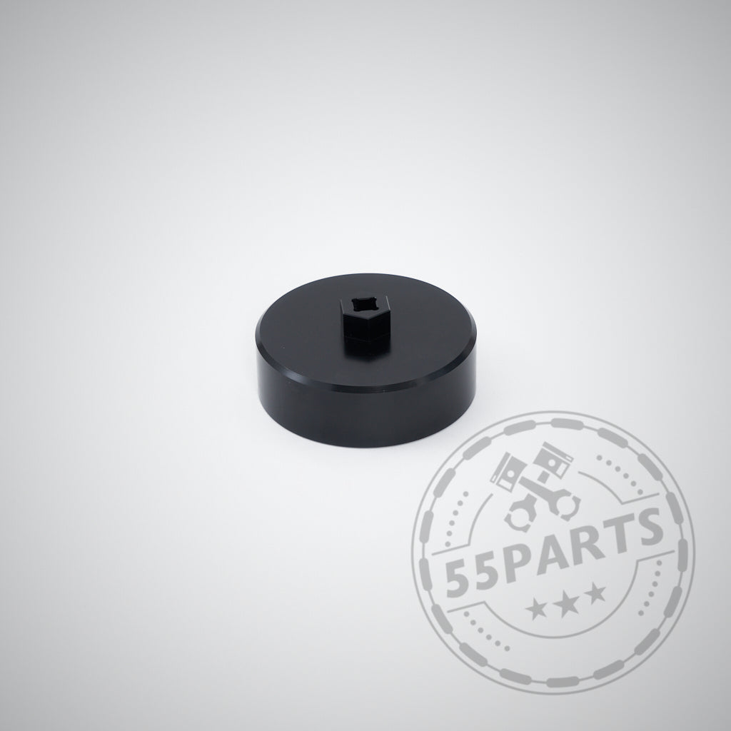 Schwarzes, rundes Metallwerkzeug mit quadratischer Mitte auf hellem Hintergrund. Das 55Parts-Logo ist sichtbar. Das exklusive 55Parts Aluminium-Ölfilter-Montagewerkzeug passt passend für BMW N20-, N52-, N53-, N54-, N55- und S55-Motoren.