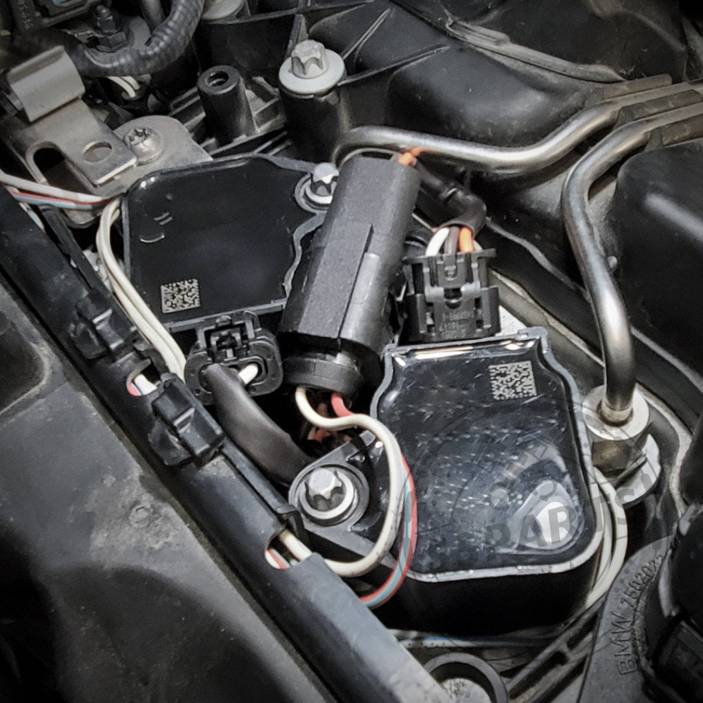 Nahaufnahme eines Automotorraums mit elektrischen Anschlüssen, Metallrohren und dem exklusiven B58-Zündspulen-Upgrade-Kit von NexSys Motorsport 55Parts passend für BMW S55/N55-Motoren (E8x, E9x, F2x, F3x, F8x).