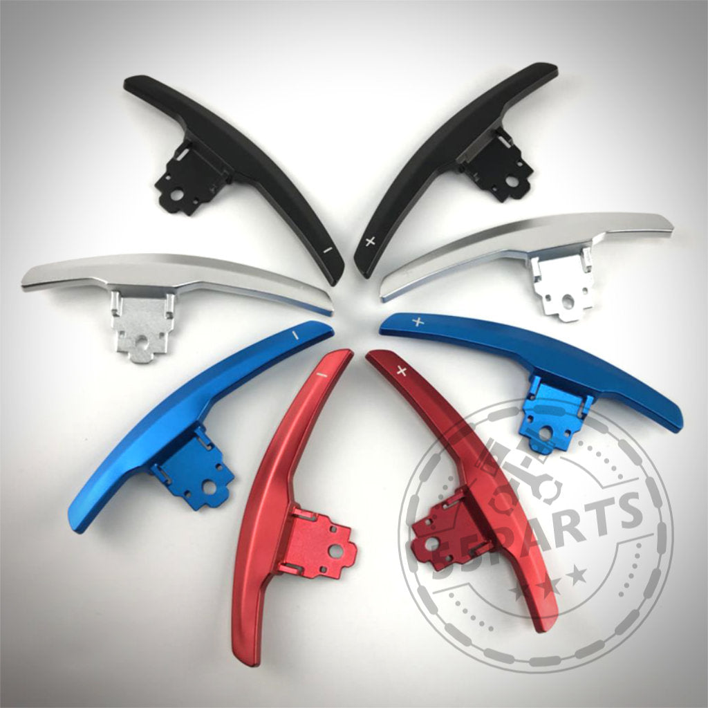 Sechs 55Parts Aluminium-/Carbon-Schaltwippen für die BMW F/G-Serie (1/235, 40i, 3/435, M2, M3, M4) werden in Rot, Blau, Silber und Schwarz in einem kreisförmigen Muster auf weißem Hintergrund angezeigt.