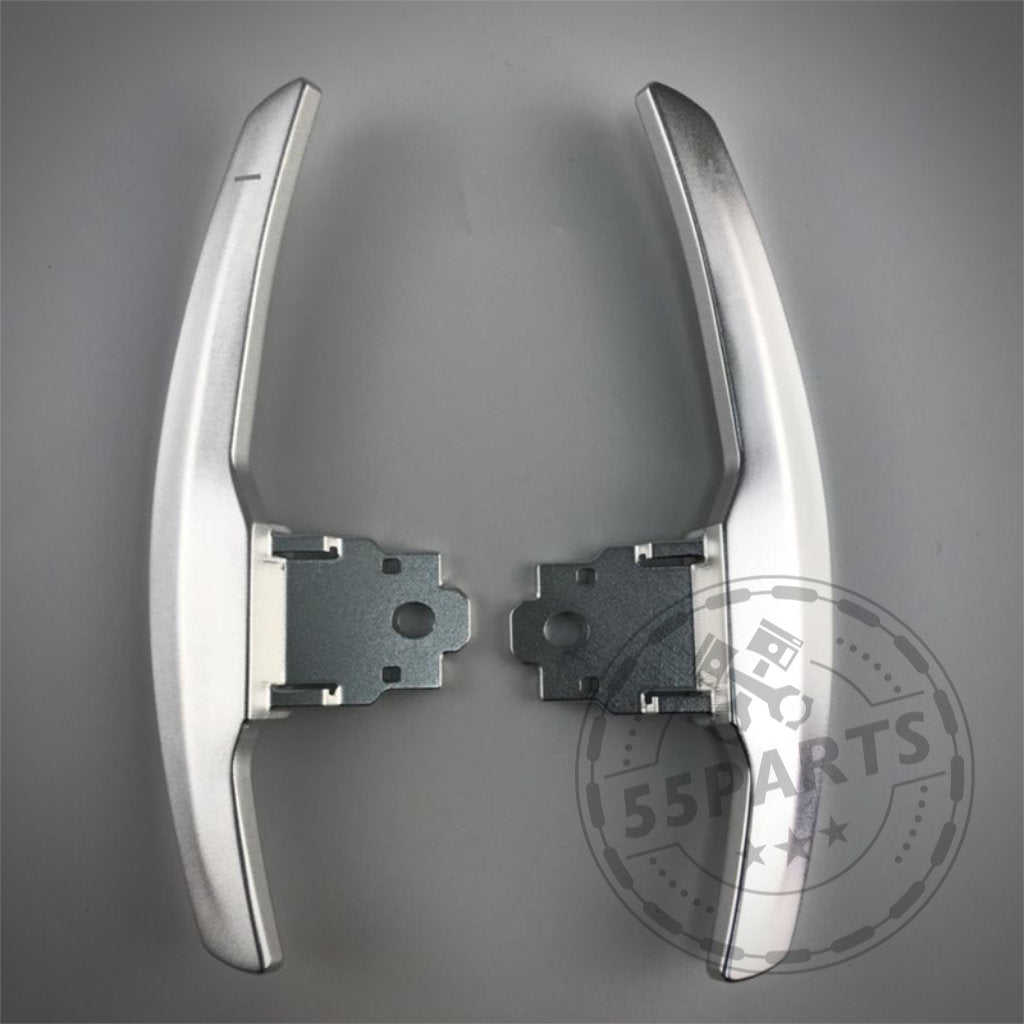 Zwei Aluminium/Carbon-Schaltwippen, entworfen für die BMW 1/235 und 40i, 3/435 und 40i, M2, M3 & M4 F- und G-Serie, werden nebeneinander auf einer grauen Oberfläche angezeigt.