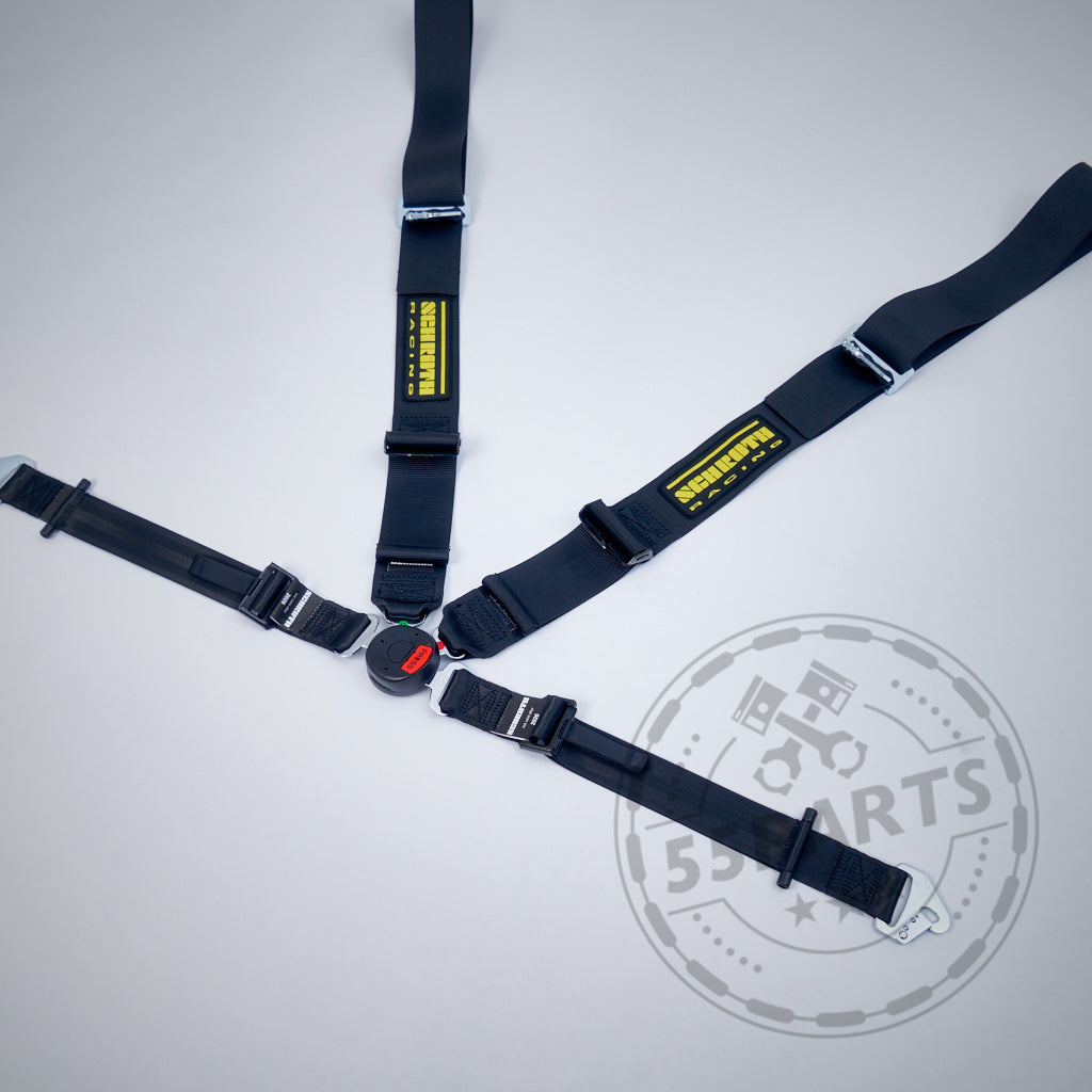 Der SCHROTH Profi II-FE 4-Punkt Gurt von Schroth ist ein schwarzer Renngurt mit gelben Etiketten auf hellgrauem Untergrund, konzipiert für die Verwendung mit 4- oder 6-Punkt-Gurten und Recaro Pole Position Schalensitzen.