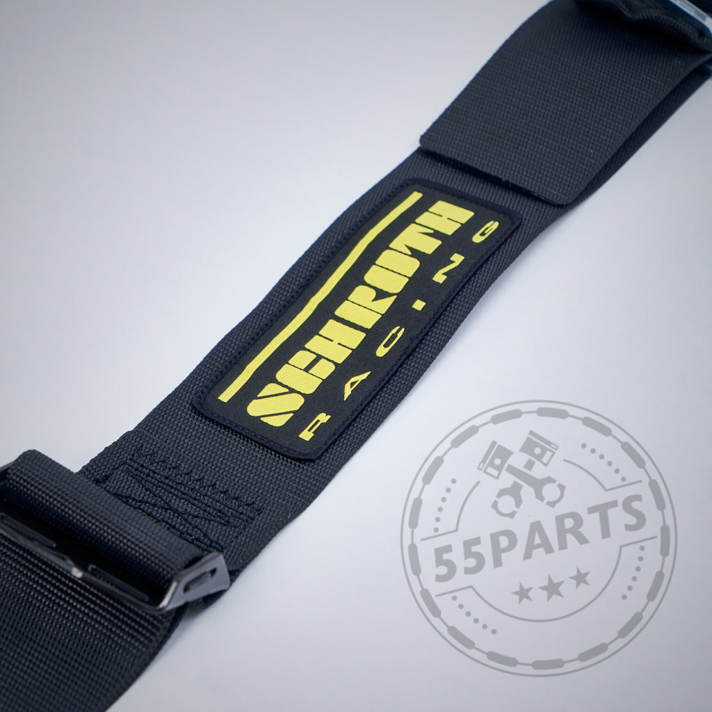 Nahaufnahme des SCHROTH Profi II-FE 4-Punkt-Gurts von Schroth mit gelbem Logo auf den Schalensitzen. Ideal für Recaro Pole Position-Sitze. Das 55Parts-Wasserzeichen ist in der unteren rechten Ecke sichtbar.