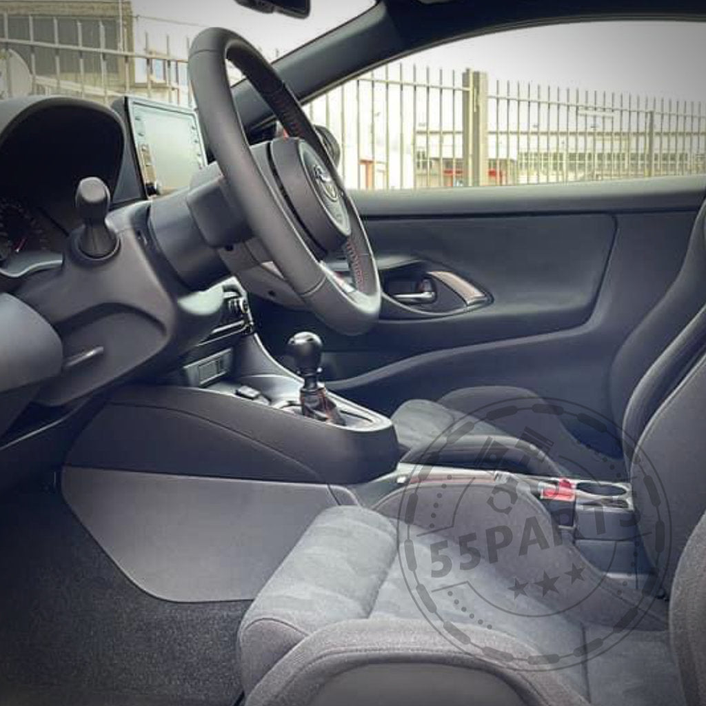 Innenraum eines Toyota GR Yaris mit Stoffsitzen, manueller Gangschaltung und Touchscreen, hervorgehoben durch den Spurverbreiterung/Lenkrad-Spacer von DDM Racing Srls (passend für GR Yaris inkl. Facelift), fotografiert von der Beifahrerseite.