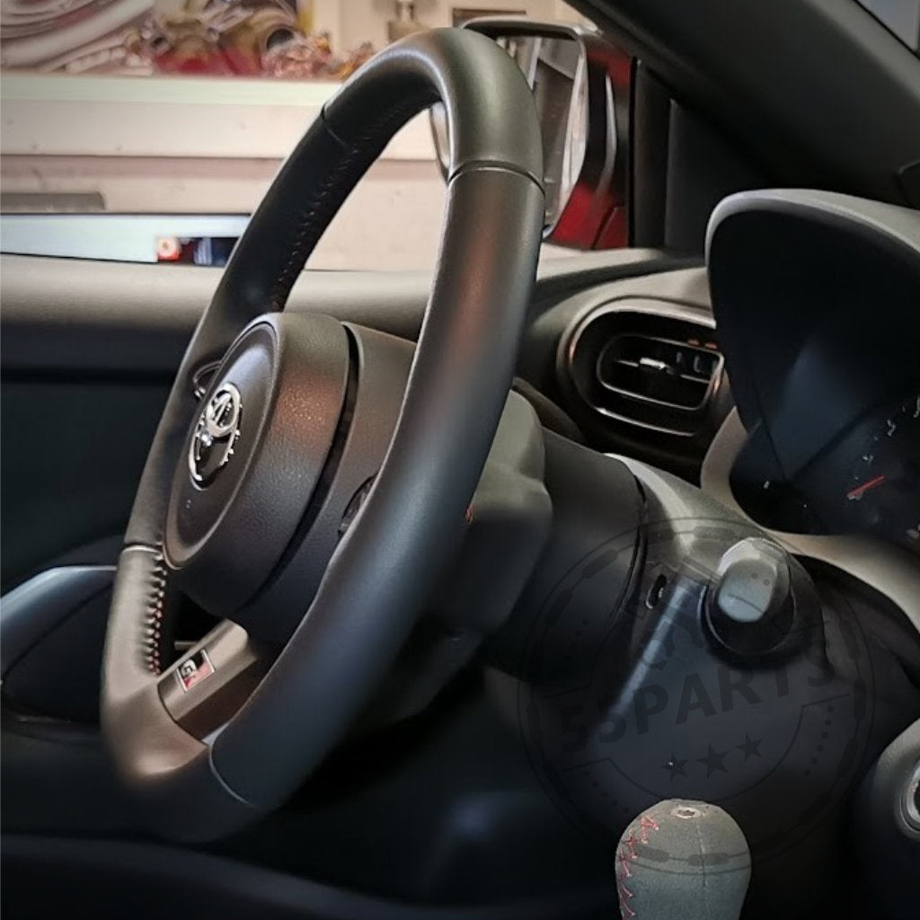 Nahaufnahme eines Lenkrad-Abstandshalters von DDM Racing Srls für den Toyota GR Yaris. Er zeigt Lenkrad und Armaturenbrett mit Fokus auf präziser Lenkradposition. Passend für alle GR Yaris-Modelle, einschließlich Facelift!.