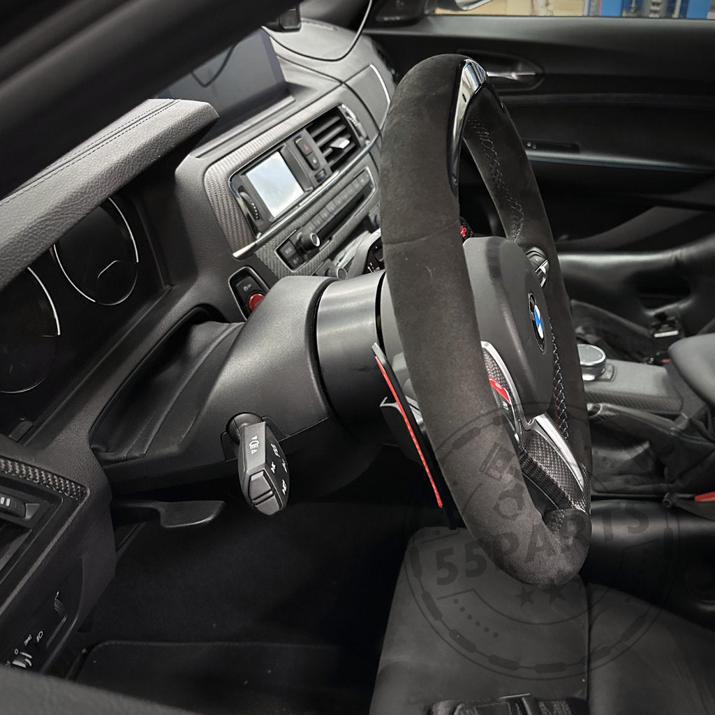 Nahaufnahme des Innenraums eines BMW F8X mit dem DDM Racing Srls Wheel Spacer / Lenkrad-Spacer, kompatibel mit allen BMW F8X M2, M3, M4 und anderen Modellen der F-Serie 1er, 2er, 3er, 4er. Mit Lenkrad, Armaturenbrett und Mittelkonsole.